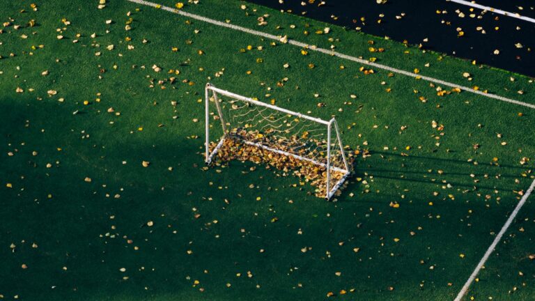Gol de futebol em campo gramado vazio, com a trave e a rede em destaque durante o dia em ambiente esportivo ao ar livre